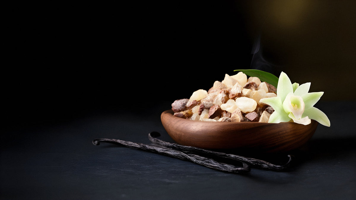 Resine aromatiche di incenso, mirra e benzoino in una ciotola di legno, con baccelli e fiore di vaniglia: le materie prime dei profumi ambrati